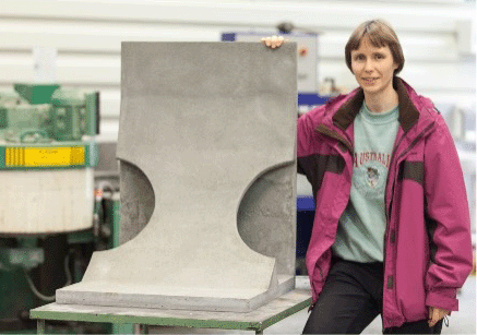 Das Bild zeigt Regine Ortlepp neben einem von ihr entwickelten TRC-Winkelstützenelement in einem Forschungslabor.