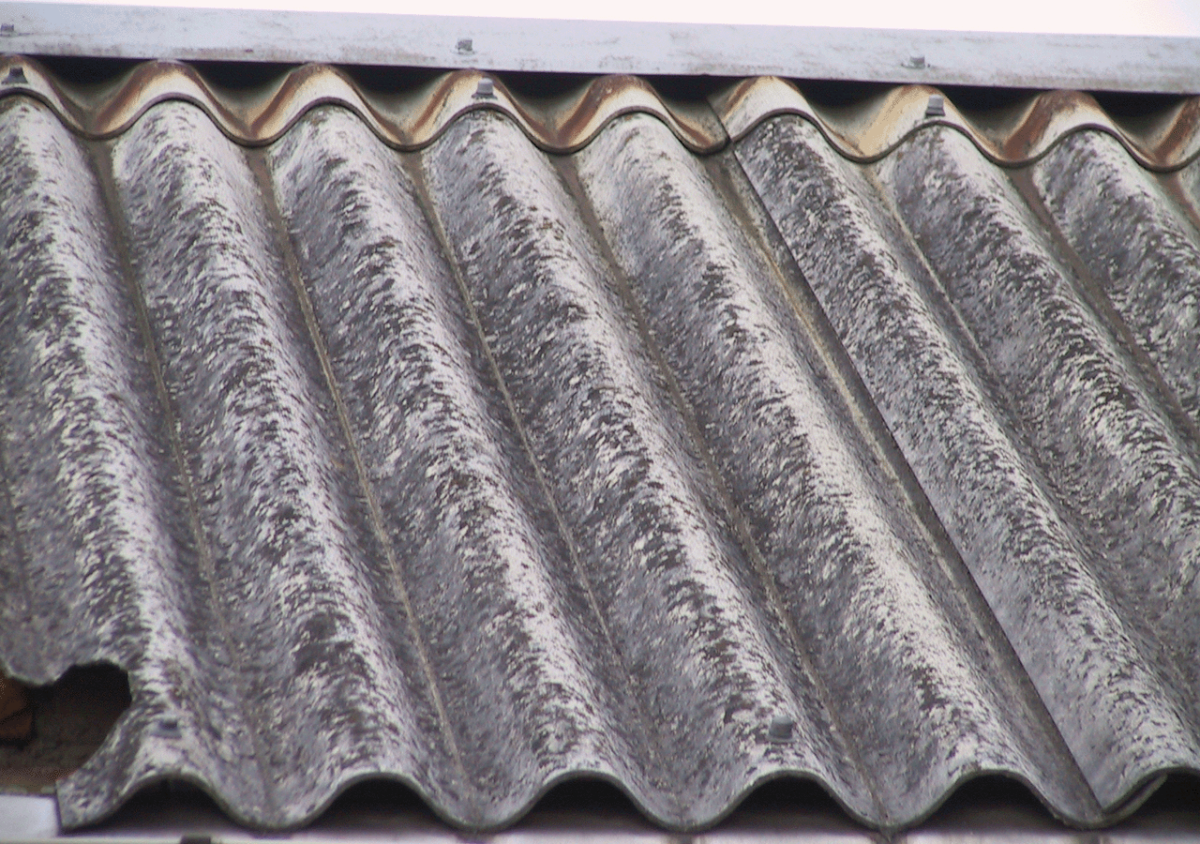 Dargestellt ist im Detail ein Wellblechdach aus schwarzen Asbestfaserplatten. Im oberen Bereich ist der freie Belüftungsabstand sowie die Abdeckung zu sehen.