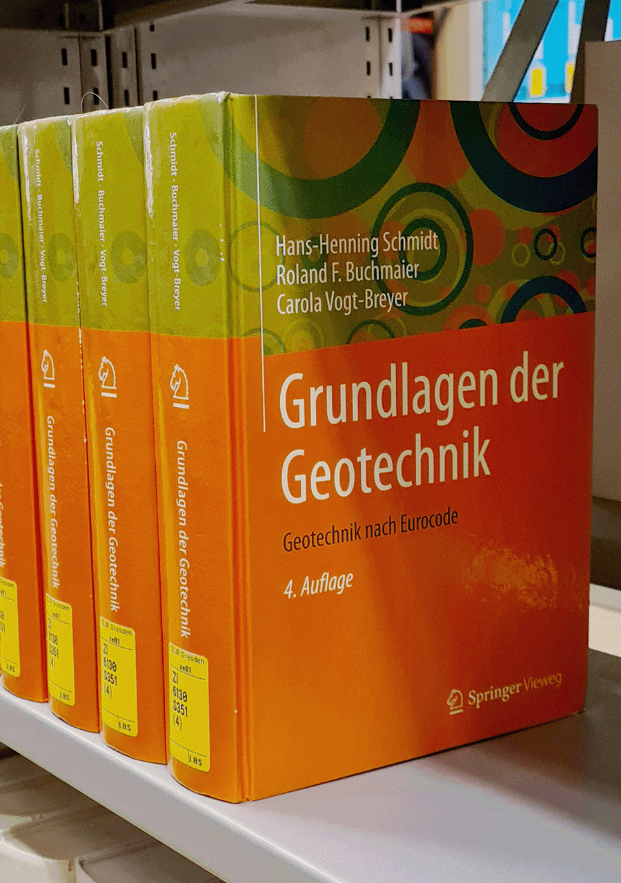 Auf dem Bild ist ein Ausschnitt eines Regals der SLUB Dresden mit einigen Büchern dargestellt. Dabei ist das Buchcover des Werks "Grundlagen der Geotechnik" zu erkennen. 
